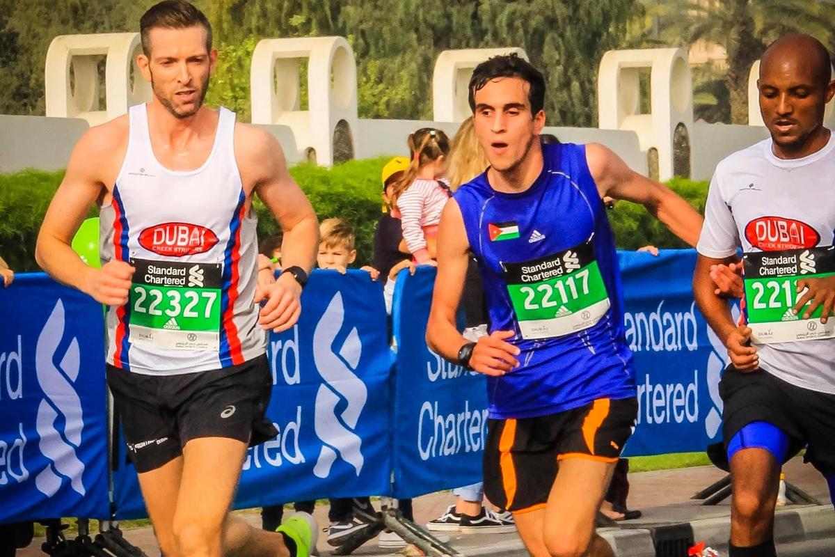 Hasan is running with two running guides beside him during the Dubai Marathon